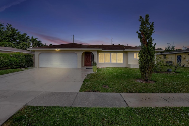 ranch-style house with a garage and a yard