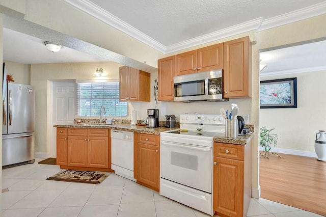 kitchen with sink, ornamental molding, light tile patterned floors, stainless steel appliances, and light stone countertops