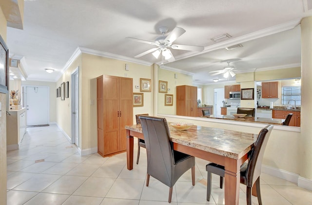 dining space featuring crown molding, sink, light tile patterned floors, and ceiling fan