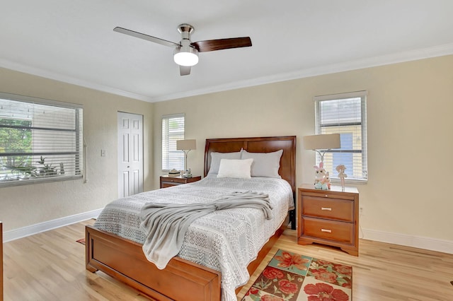 bedroom with ornamental molding, light wood-type flooring, ceiling fan, and a closet