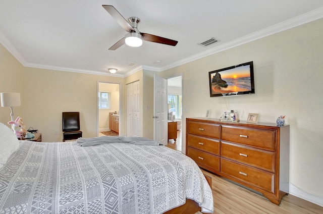 bedroom featuring light hardwood / wood-style flooring, ornamental molding, ceiling fan, ensuite bath, and a closet