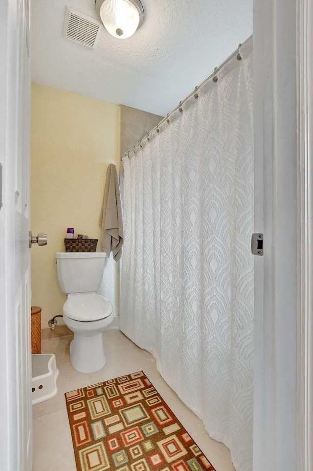 bathroom featuring tile patterned flooring, a textured ceiling, and toilet