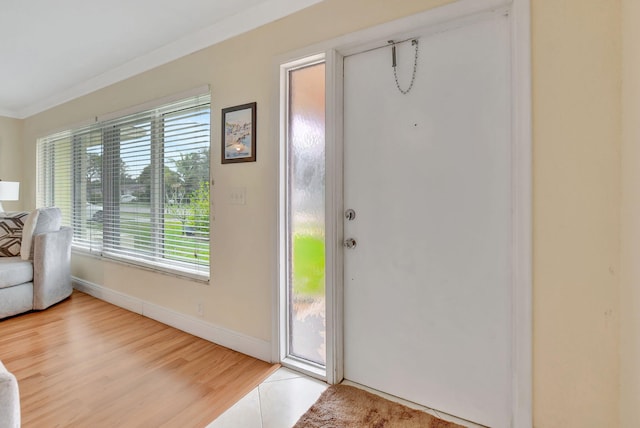 entryway with ornamental molding, a wealth of natural light, and light hardwood / wood-style floors