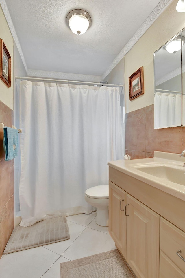 bathroom with tile walls, tile patterned flooring, vanity, ornamental molding, and a textured ceiling