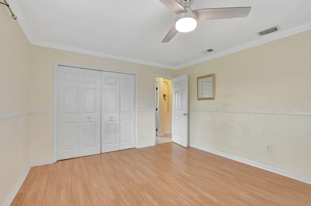 unfurnished bedroom featuring crown molding, light hardwood / wood-style floors, a closet, and ceiling fan