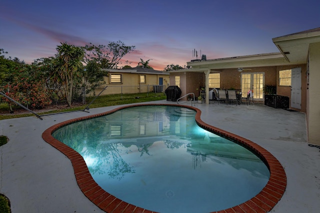 pool at dusk featuring a patio and ceiling fan