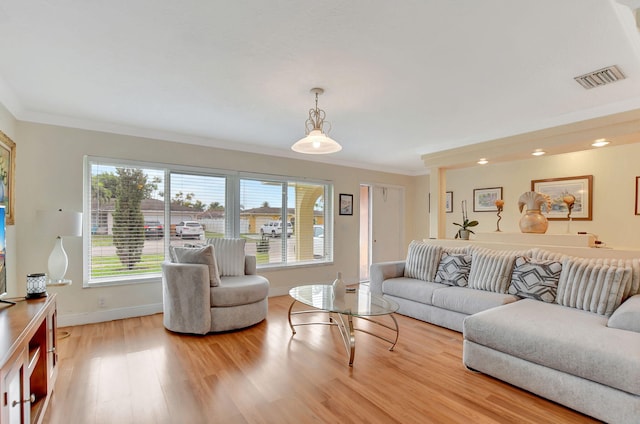 living room with ornamental molding and light hardwood / wood-style flooring