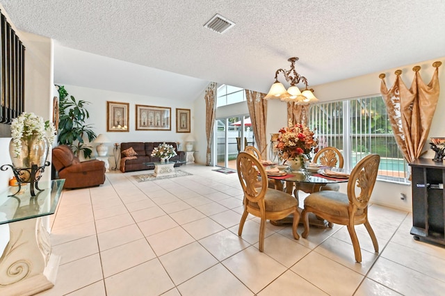 tiled dining space featuring an inviting chandelier, lofted ceiling, and a textured ceiling