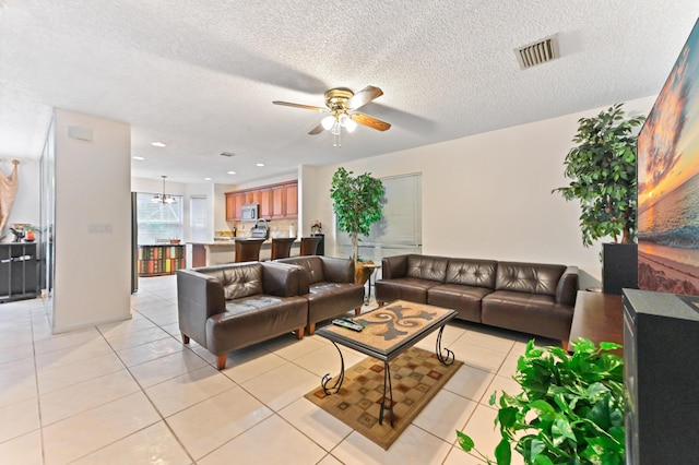 tiled living room with ceiling fan and a textured ceiling