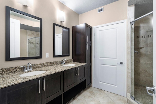 bathroom featuring a textured ceiling, a shower with shower door, tile patterned floors, and vanity