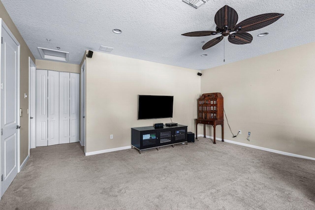 carpeted living room featuring ceiling fan and a textured ceiling