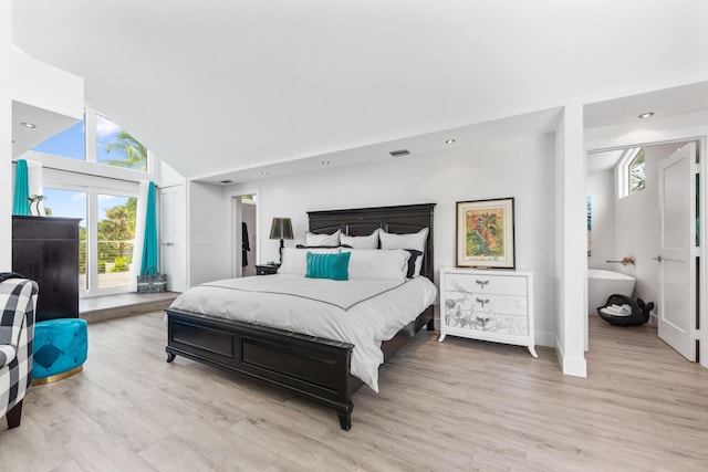 bedroom featuring light hardwood / wood-style flooring, high vaulted ceiling, and ensuite bathroom