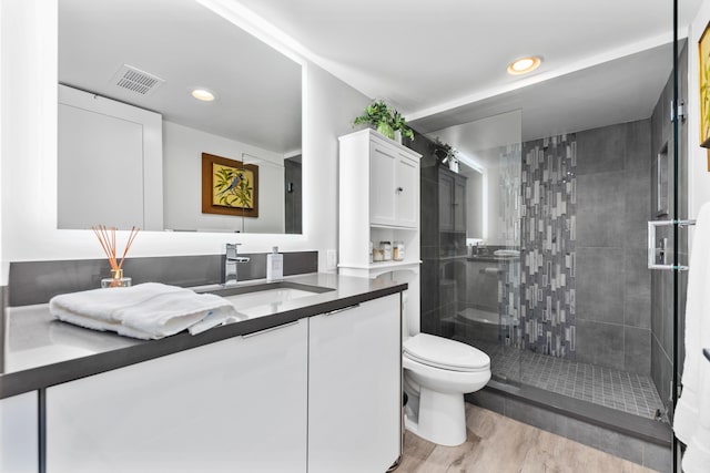 bathroom with vanity, toilet, a shower with door, and hardwood / wood-style flooring