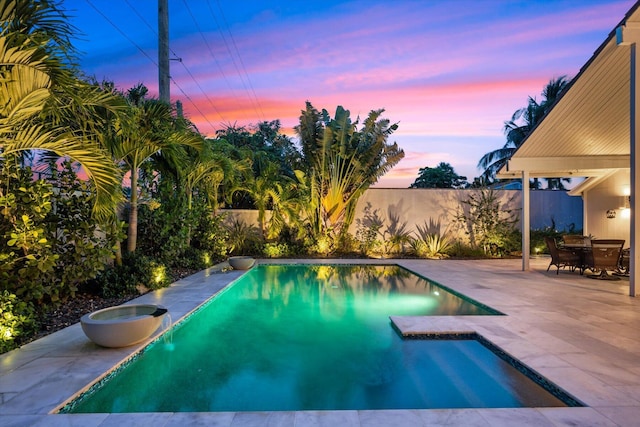 pool at dusk featuring a patio