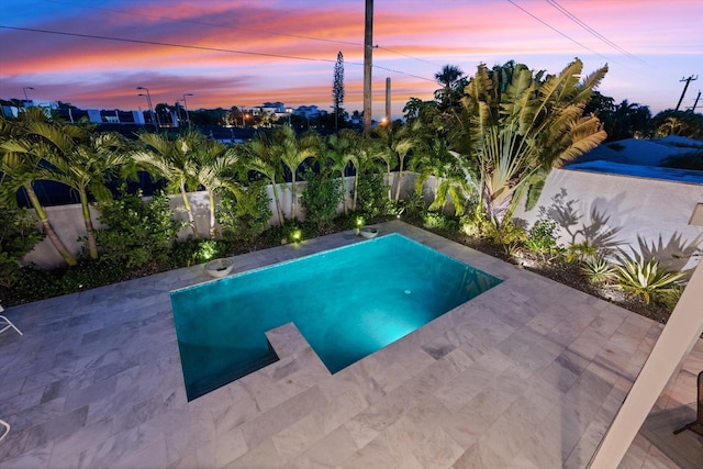 pool at dusk featuring a patio area