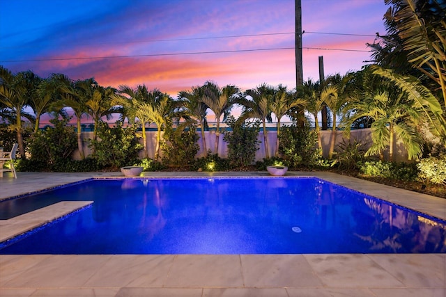 pool at dusk featuring a patio area