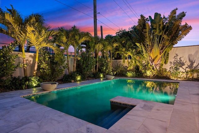 pool at dusk with a patio area