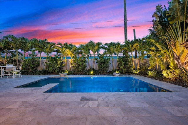 pool at dusk featuring a patio