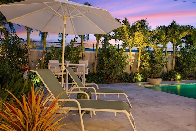 patio terrace at dusk with a fenced in pool