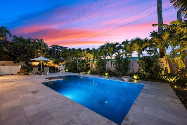 pool at dusk featuring a patio area