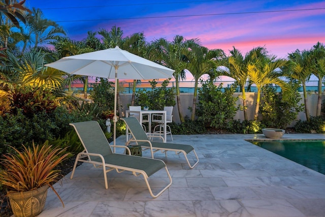 patio terrace at dusk with a fenced in pool