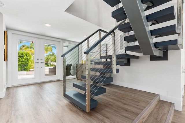 stairway with french doors and hardwood / wood-style floors