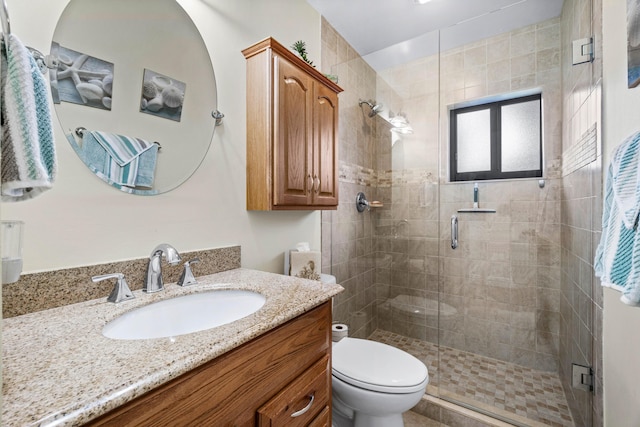 bathroom with a shower with shower door, toilet, and vanity