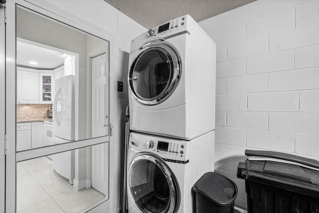 laundry room with stacked washer / dryer and a textured ceiling