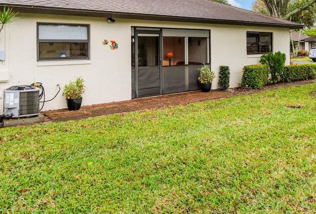 rear view of property featuring central AC unit and a lawn