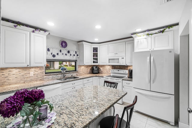 kitchen featuring light stone countertops, white appliances, white cabinetry, sink, and light tile patterned flooring