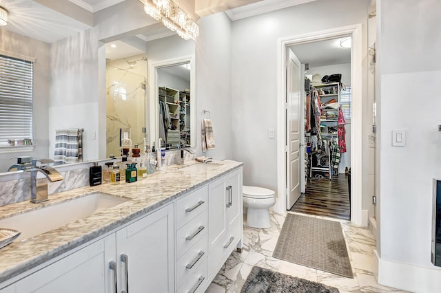 bathroom featuring a shower with shower door, toilet, vanity, and ornamental molding