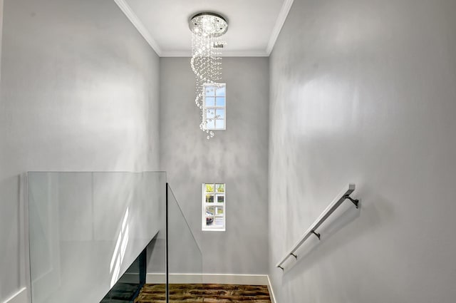 stairway with a notable chandelier, a healthy amount of sunlight, hardwood / wood-style floors, and ornamental molding