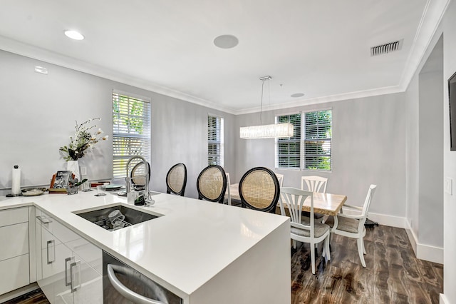 kitchen featuring crown molding, dishwasher, sink, white cabinets, and decorative light fixtures