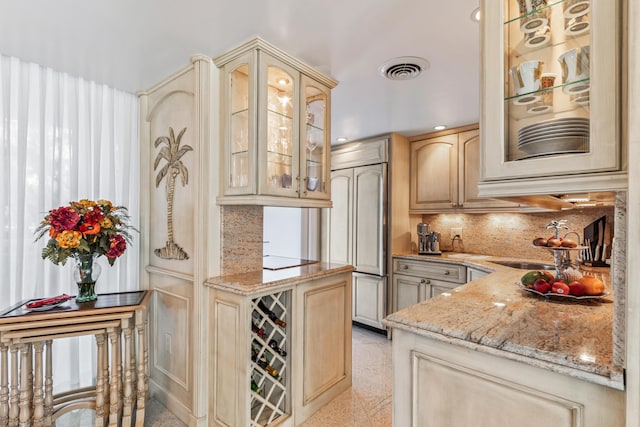 kitchen with tasteful backsplash, paneled built in refrigerator, light stone countertops, and light brown cabinetry