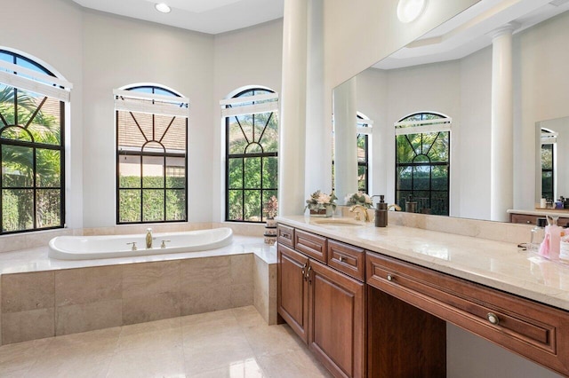 bathroom with vanity, tiled bath, and a healthy amount of sunlight