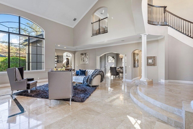 living room with ornate columns, ornamental molding, and a high ceiling