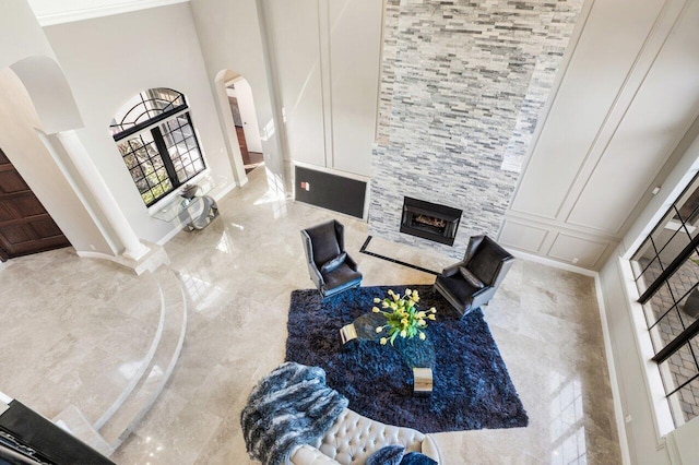 living room featuring a stone fireplace and a towering ceiling