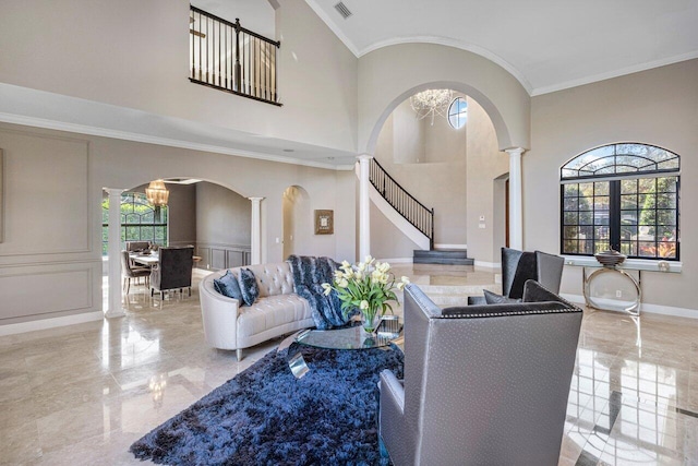 living room with crown molding, a towering ceiling, and ornate columns