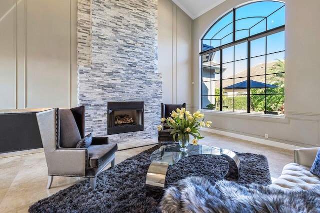 living room featuring crown molding, a towering ceiling, and a stone fireplace