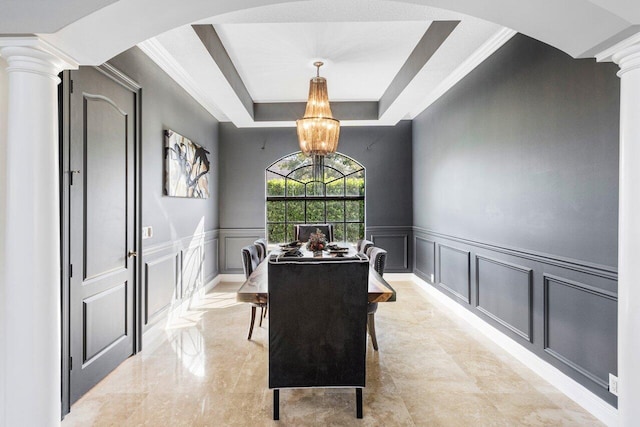 dining room featuring an inviting chandelier, decorative columns, and a raised ceiling