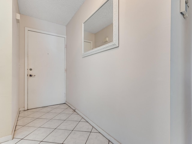 doorway featuring a textured ceiling and light tile patterned floors