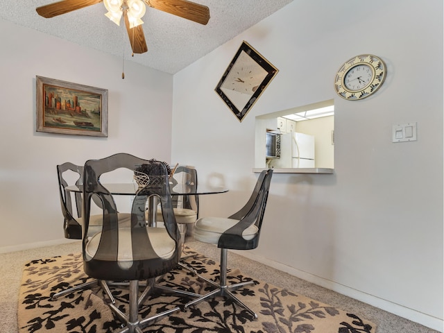 dining room featuring ceiling fan, carpet floors, and a textured ceiling