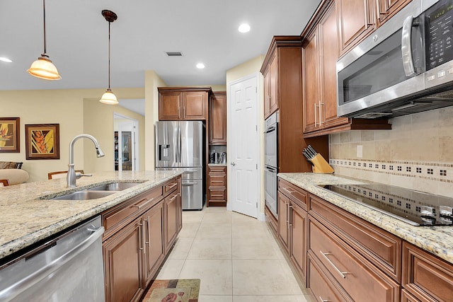 kitchen with sink, stainless steel appliances, light stone countertops, and pendant lighting