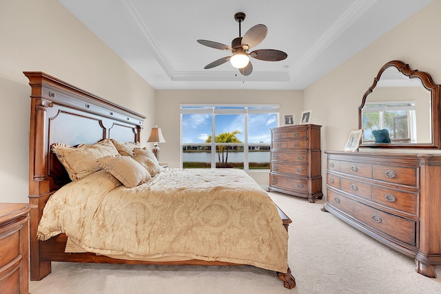 carpeted bedroom with ceiling fan, a water view, and a raised ceiling