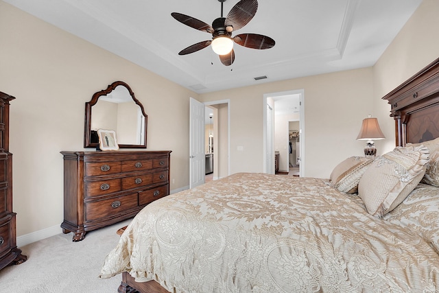 bedroom with light carpet, a tray ceiling, and ceiling fan