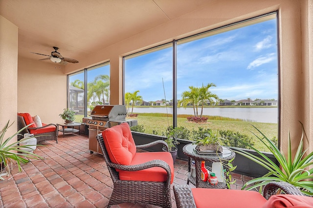 sunroom / solarium featuring ceiling fan and a water view