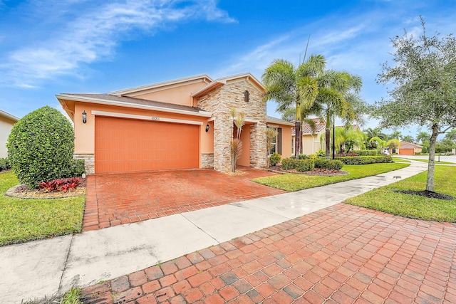 10211 SW Fernwood Ave, Port Saint Lucie, FL 34987 - view of front of property featuring a front lawn, an attached garage, decorative driveway, stone siding, and stucco siding
