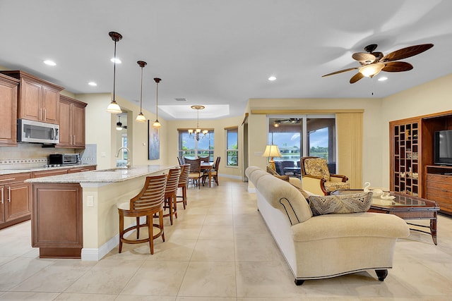 tiled living room with sink and ceiling fan with notable chandelier