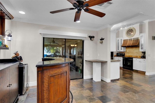 kitchen featuring wall chimney exhaust hood, backsplash, white cabinets, and ornamental molding