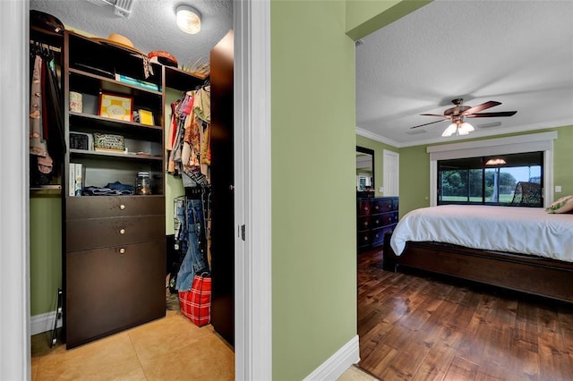 bedroom with wood-type flooring, a textured ceiling, ceiling fan, and ornamental molding